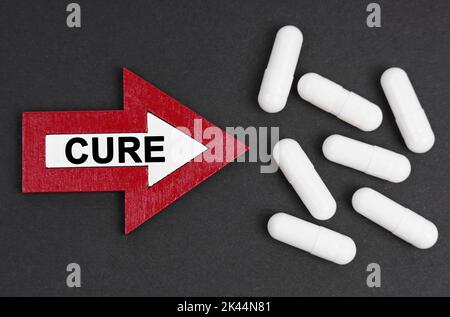 Concept de médecine. Les tablettes sont sur fond noir. Ils sont indiqués par une flèche sur laquelle il est écrit - CURE Banque D'Images