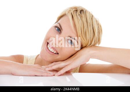 Quel beau sourire. Portrait d'une jolie jeune femme se reposant sur ses mains alors qu'elle est isolée sur le blanc. Banque D'Images