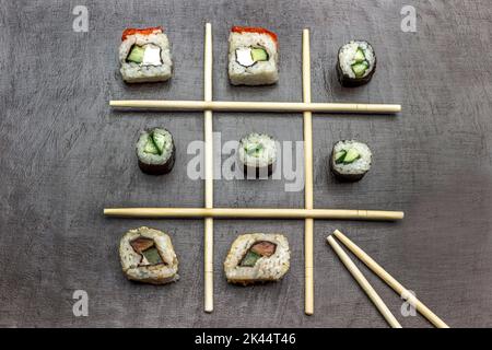 Les baguettes sont disposées en diagonale, les sushis se trouvent entre les baguettes. Copier l'espace. Pose à plat. Arrière-plan marron
