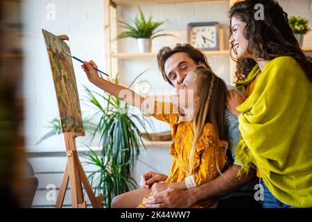 Concept de famille heureux. Les jeunes parents et les enfants peignent ensemble à la maison. Les gens s'amusent. Banque D'Images