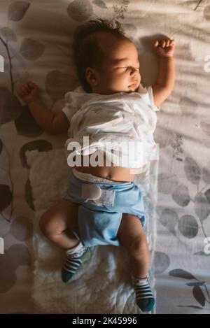 bébé nouveau-né portant une couche de tissu dormant paisiblement dans le lit le matin avec lumière naturelle et pyjama blanc Banque D'Images