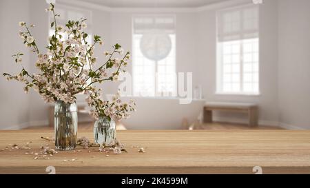 Table, bureau ou étagère en bois gros plan avec branches de cerisiers en fleurs dans un vase en verre, vue floue sur la salle de bain spa scandinave avec baignoire, boho Banque D'Images