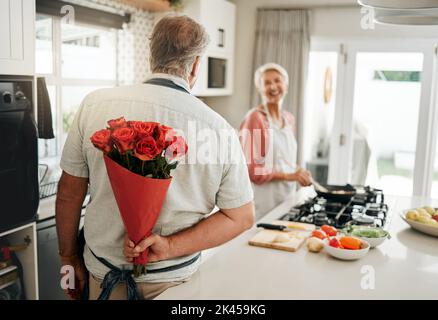 Roses, cadeau et couple senior aiment les fleurs pour célébrer leur anniversaire de mariage d'une manière romantique à la maison. Romance, heureux et vieux homme donnant à la femme un Banque D'Images