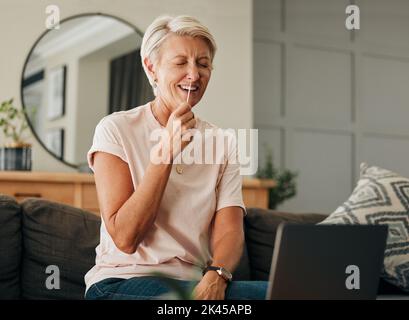 Covid, ordinateur portable et pcr avec femme âgée riant pendant la consultation en ligne ou vidéo de tutoriel pour l'auto-test de l'antigène kit rapide sur le canapé à la maison. Vieille dame Banque D'Images