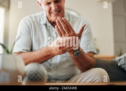 Homme âgé, mains et douleurs articulaires au poignet dans la maison de salon à cause du tunnel carpien, de l'ostéoporose et de l'arthrite. Homme âgé, malade et stressant, orthopédique Banque D'Images