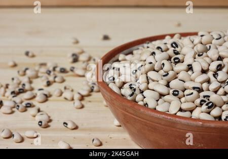 Petits pois noirs séchés non cuits dans un bol sur une table en bois Banque D'Images