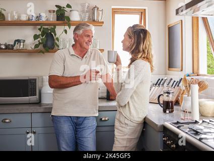Couple âgé, café et cuisine sourient, conversation et matin ensemble dans leur maison. L'homme, la femme et la retraite dans le lien de maison, heureux et de détente Banque D'Images