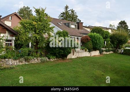 Vue sur le champ d'herbe verte et les maisons familiales typiques de la campagne suisse dans le canton de Zurich. Banque D'Images