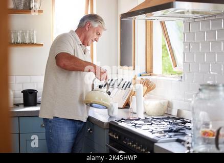 Homme de retraite et bouilloire pour le thé dans la cuisine préparation pour la boisson de loisirs dans la maison de Nouvelle-Zélande. Senior, en bonne santé et mature gars appréciant la pension Banque D'Images