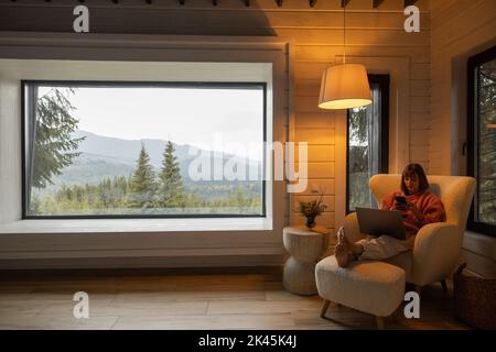 Femme travaille sur ordinateur portable à la maison dans les montagnes Banque D'Images