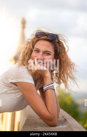 Jeune insouciante caucasienne 30s positive femme avec des cheveux bouclés souriant dehors Banque D'Images