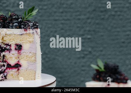 La moitié d'un gâteau au chocolat et aux baies se rapproche sur fond gris Banque D'Images