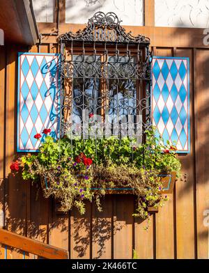 Fenêtre de style bavarois traditionnel avec volets et boîte à fenêtre avec plantes géraniums Banque D'Images