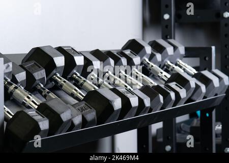 Dumbbbbbell salle de gym mur maison floue ensemble de stockage strongman poids corporel, concept équipement de fitness dans lourd de musclé fort, activité culturisme Banque D'Images