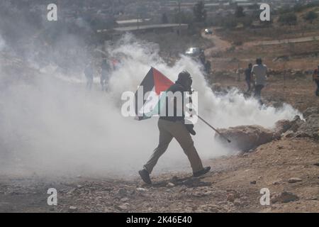 Naplouse, Palestine. 30th septembre 2022. Un manifestant palestinien fuit des canisters à gaz lacrymogène tirés par les forces israéliennes lors de la manifestation contre les colonies israéliennes dans le village de Beit Dajan, près de la ville de Naplouse, en Cisjordanie. (Photo de Nasser Ishtayeh/SOPA Images/Sipa USA) crédit: SIPA USA/Alay Live News Banque D'Images