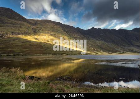 Le soleil se brisant à travers les nuages peint les pentes de montagne de Glencoe en Écosse Banque D'Images