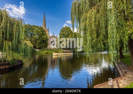 Un bateau de croisière sur la rivière et une église de la Sainte Trinité de l'autre côté de la rivière à Stratford-upon-Avon, Warwickshire, Angleterre Banque D'Images