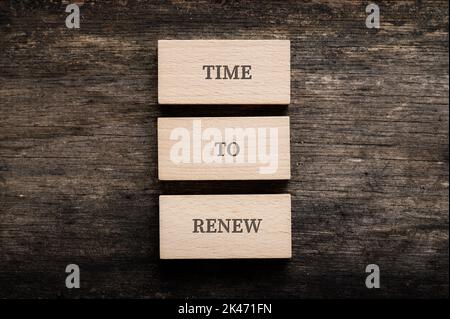 Il est temps de renouveler l'affiche orthographiée sur trois blocs de bois empilés placés sur un arrière-plan rustique en bois. Banque D'Images