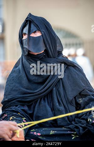 Femme avec 'battoulah' noir (masque facial) au marché du bétail vendredi matin, Nizwa, Oman Banque D'Images