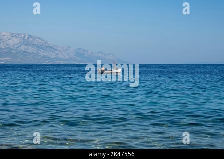 Mimice, Croatie-17 août 2022: Homme dans le bateau à moteur passant lentement au-dessus de la mer Adriatique calme, au large de la côte de Mimice, Croatie avec la Bio intimidante Banque D'Images