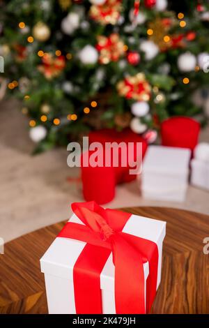 Boîtes cadeau de Noël avec ruban rouge et des cônes de pin près de l'arbre dans la salle de séjour.Un arbre de Noël joliment décoré avec beaucoup de jolis emballés Banque D'Images