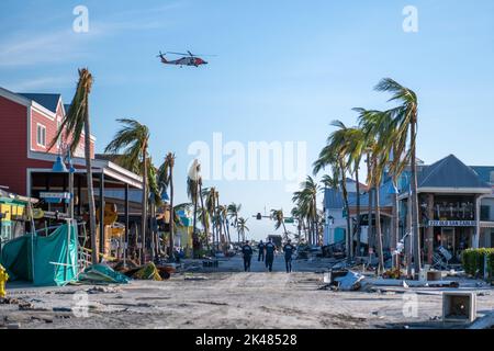 À la suite de l'ouragan Ian, un hélicoptère Jayhawk de la Garde côtière vole au-dessus de la tête, tandis que les équipes de la Force nationale de grève de la Garde côtière effectuent des recherches et des opérations de sauvetage en milieu urbain pour des personnes disparues à fort Myers Beach, en Floride, sur 29 septembre 2022. (ÉTATS-UNIS) Banque D'Images