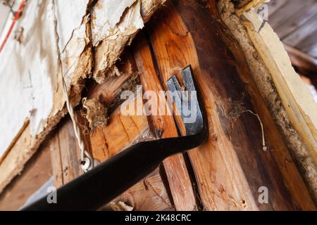 L'arrache-clou noir enlève un clou de l'ancien mur en bois Banque D'Images