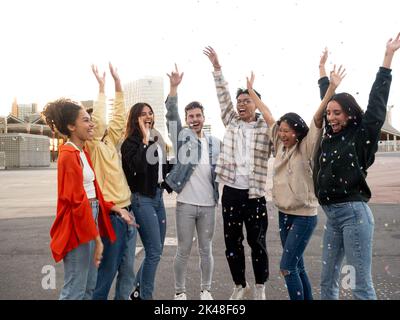 Groupe d'amis du millénaire multiethniques appréciant la fête et le lancement de confetti. Des amis qui s'amusent Banque D'Images