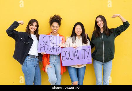 Groupe de jeunes femmes multiethniques avec des signes féministes sur fond jaune. Féminisme, les femmes habilitées Banque D'Images