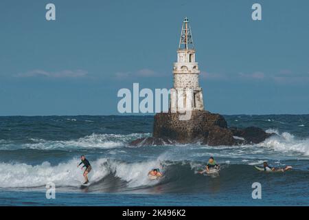 AHTOPOL, BULGARIE - 17 septembre 2022 : les surfeurs attrapent d'énormes vagues près du célèbre phare d'Ahtopol au coucher du soleil Banque D'Images