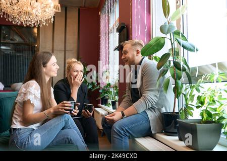 Deux femmes et leur compagnon appréciant leur pause-café Banque D'Images