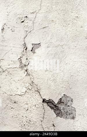 Paroi plâtrée fissurée peinte en blanc avec fissures. Ancienne surface endommagée. Élément d'image d'arrière-plan haute résolution avec espace de copie, emplacement de texte. Banque D'Images