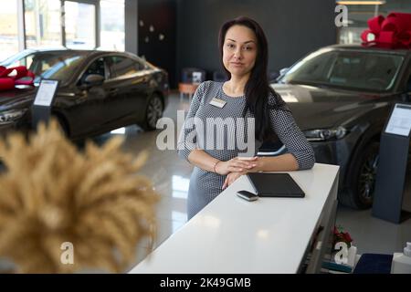 Femme directrice de centre de voiture se tient sur le fond de nouvelles voitures Banque D'Images