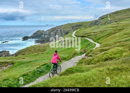 Belle femme senior en VTT, en vélo sur les falaises de Malin Head, le point le plus au nord de l'Irlande Banque D'Images