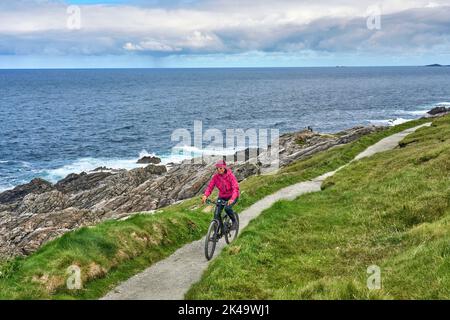 Belle femme senior en VTT, en vélo sur les falaises de Malin Head, le point le plus au nord de l'Irlande Banque D'Images