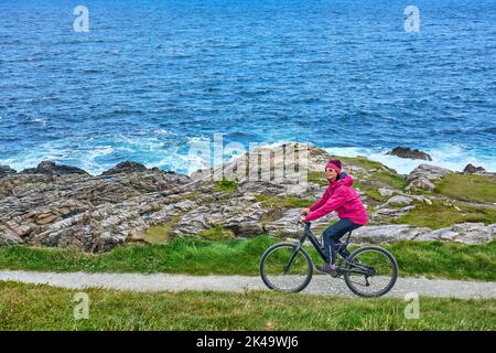 Belle femme senior en VTT, en vélo sur les falaises de Malin Head, le point le plus au nord de l'Irlande Banque D'Images