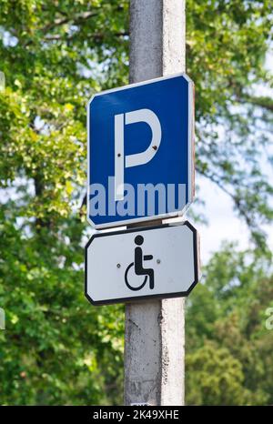 Un cliché vertical d'un poteau métallique avec un panneau de stationnement bleu destiné aux conducteurs handicapés Banque D'Images