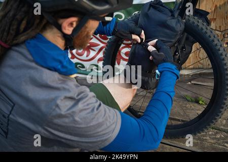 Homme avec des dreadlocks et fermer son sac touristique à vélo de montagne près de la maison Nomad Yurt à Almaty, Kazakhstan. Vélo Extreme Sport, bikepacking et out Banque D'Images