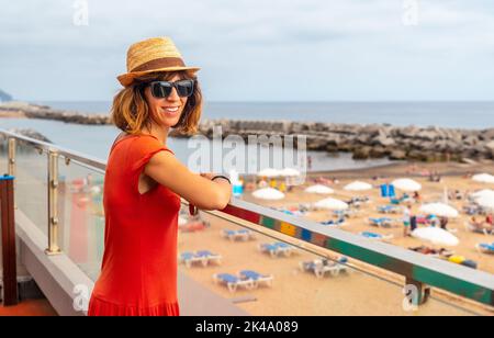 Portrait d'une jeune touriste vêtue d'une robe rouge sur la plage Praia da Calheta en été, Madère. Banque D'Images