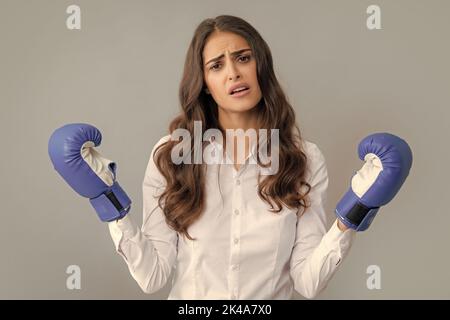 Femme triste en colère dans des gants de boxe. Une femme d'affaires prospère a des gants de boxe tout en portant une chemise isolée sur fond gris. Banque D'Images