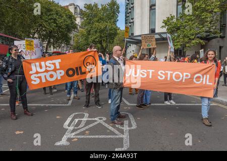 Londres, Royaume-Uni. 1er octobre 2022. Des militants écologistes tiennent de grandes banderoles orange indiquant « JUST STOP OIL » lors d'une manifestation dans le centre de Londres. La manifestation appelle à la fin de l'extraction et des investissements dans les combustibles fossiles. Les manifestants occupent une piste cyclable et une rue urbaine, avec des panneaux faisant référence à l'action climatique et aux revendications spécifiques de Londres. Le groupe écologiste Just Stop Oil proteste dans les rues de Londres. Penelope Barritt/Alamy Live News Banque D'Images