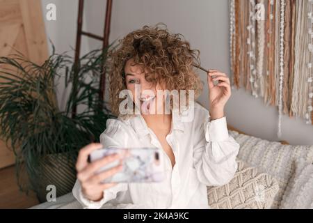 Femme ravie de montrer la langue et de prendre une photo de soi à la maison Banque D'Images