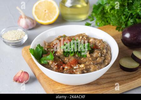 Baba ghanoush ou hummus d'aubergine dans un bol blanc sur bois, cuisine traditionnelle du Moyen-Orient, gros plan Banque D'Images