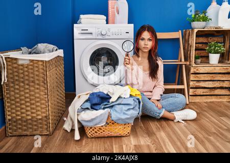 Jeune femme caucasienne utilisant la loupe à la recherche de taches dans la lessive sale attitude de pensée et d'expression sobre regardant de soi-même confiant Banque D'Images