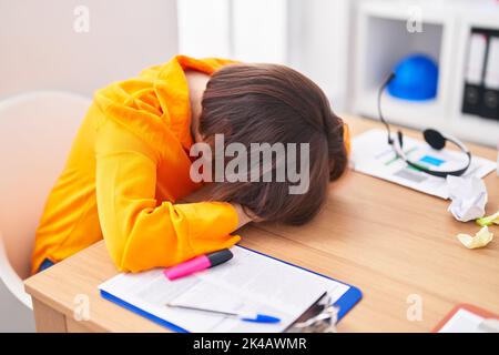 Femme d'âge moyen travailleur d'affaires stressé avec la tête sur la table au bureau Banque D'Images