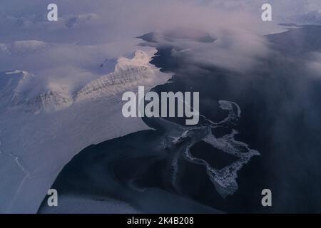 Photos aériennes uniques du paysage hivernal gelé et enneigé des montagnes et de la côte du Svalbard, prises depuis un avion / drone au coucher du soleil Banque D'Images