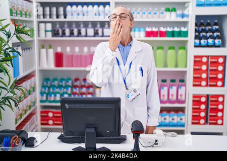 La jeune femme caucasienne travaillant à la pharmacie s'est ennuie bâilling fatiguée couvrant la bouche avec la main. Agité et somnolence. Banque D'Images