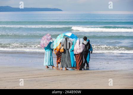 Des femmes musulmanes et un jeune homme regardant la mer à la plage de Bali, en Indonésie Banque D'Images
