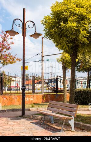Une lampe de rue, un banc en bois doré. Saison d'automne. Gare en arrière-plan. Banque D'Images
