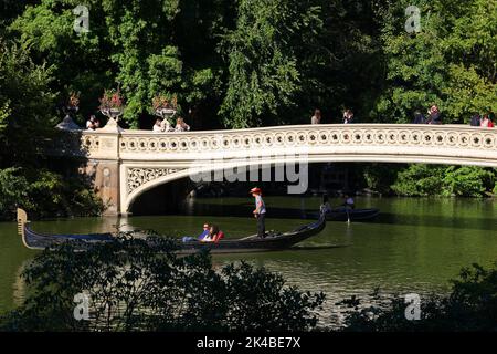 Une télécabine passe sous le pont Bow dans Central Park, New York. Bow Bridge s'étend sur le lac reliant Bethesda Terrace au ramble Banque D'Images